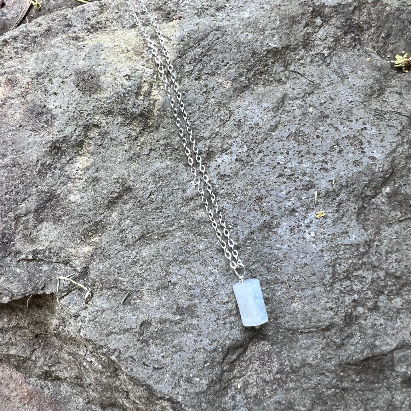 Necklace with a blue pendant on a stone surface