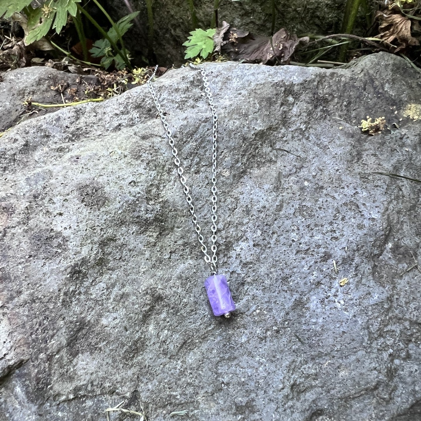 Necklace with a purple pendant on a rock