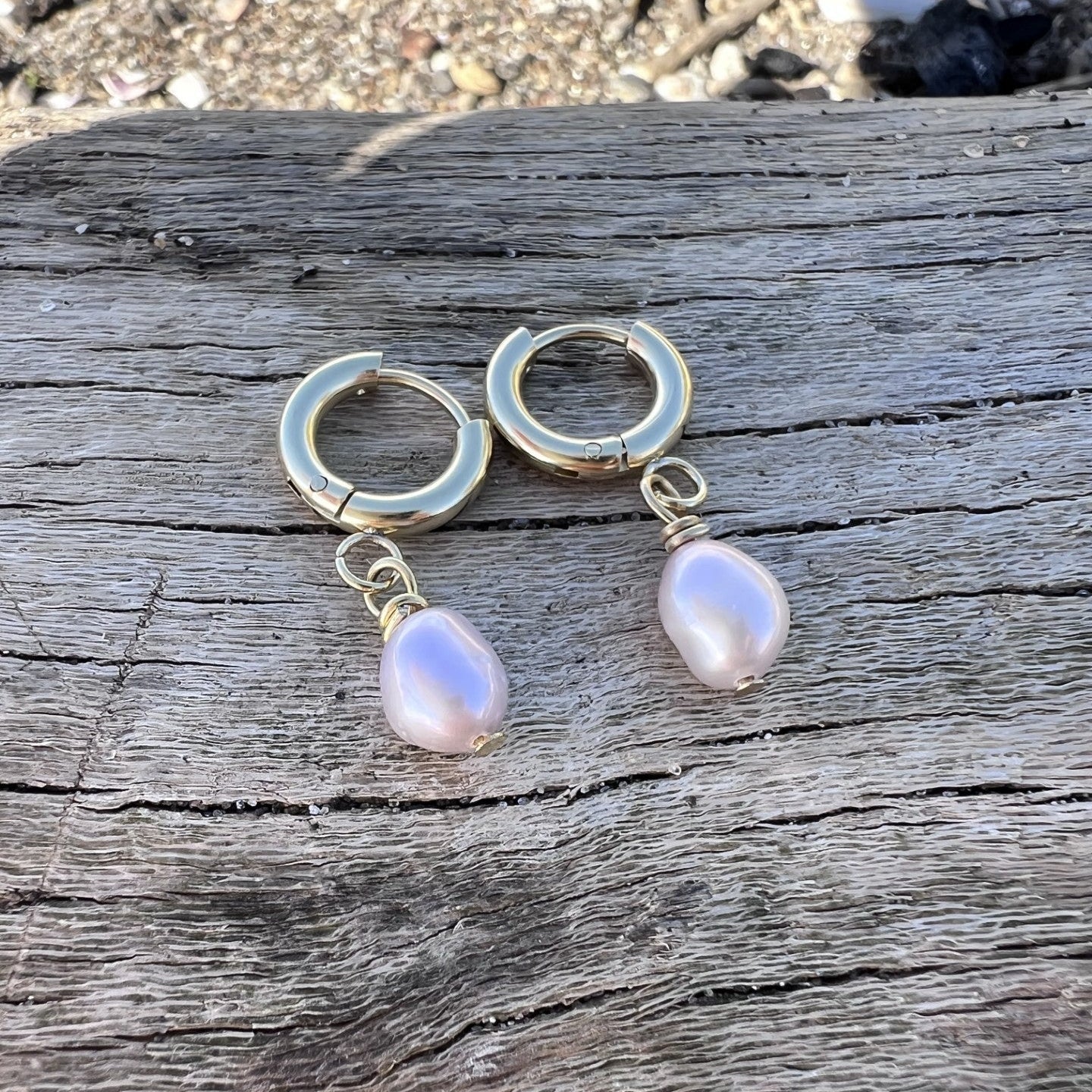 Pair of earrings with pink gemstones on a wooden surface