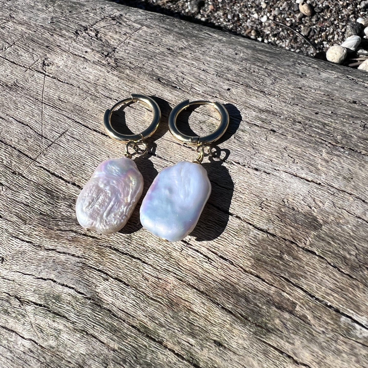 Hoop earrings with pebble-like charms on a wooden surface